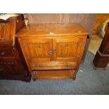 AN OAK LINENFOLD CUPBOARD WITH A DRAWER BELOW