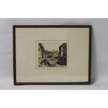 A FRAMED AND GLAZED ENGRAVING DEPICTING A CONTINENTAL STREET SCENE, signed in pencil