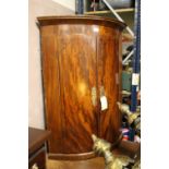 A 19TH CENTURY FLAME MAHOGANY BOW FRONTED HANGING CORNER CUPBOARD - KEY