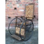 AN ANTIQUE OAK AND TAPESTRY SEAT INVALID CHAIR, with original spoked wheels