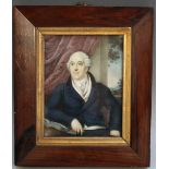 A 19TH CENTURY PORTRAIT MINIATURE OF A SEATED GENTLEMAN IN A BLUE COAT WITH BOOK BY HIS SIDE,