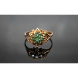 A HALLMARKED 9 CARAT GOLD EMERALD RING, having seven emeralds in a floral type setting, ring size U