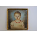 A 19TH CENTURY PORTRAIT MINIATURE OF A YOUNG GIRL WITH RED NECKLACE AND WHITE DRESS, in a gilt metal