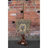 A VICTORIAN WALNUT AND BRASS POLE SCREEN, the lower walnut section with three carved and shaped