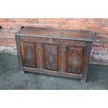 A PROVINCIAL ANTIQUE OAK COFFER, the hinged lid above a three panel front, raised on stile feet,