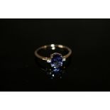 A HALLMARKED 9 CARAT GOLD TANZANITE RING, the oval tanzanite coming with a stone either side, and is