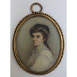 M. D. A late 19th / early 20th century oval portrait miniature of a lady in a white dress, in gilt