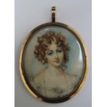 A LATE 19TH / EARLY 20TH CENTURY OVAL PORTRAIT MINIATURE OF A YOUNG WOMAN WITH RINGLETS, in gilt