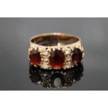 A TRIPLE GARNET RING, set in yellow metal the garnets are separated by three white stones each, ring