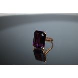 A LARGE EMERALD CUT AMETHYST RING, measuring approx 18mm x 14mm, set in unmarked yellow metal,