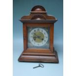 AN EDWARDIAN OAK CASED MANTEL CLOCK WITH SILVERED DIAL, the architectural case with carved detail,