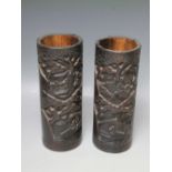 A PAIR OF ORIENTAL HARDWOOD CARVED BRUSH POTS, each typically carved with figures in a wooded