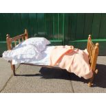 A VICTORIAN OAK FRAMED DOLLS BED, with wire/mesh base, complete with bedding, L 75.5 cm, D 33 cm,