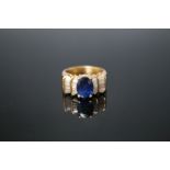 AN 18K SAPPHIRE AND DIAMOND RING, the central oval sapphire measuring approx 9mm by 6mm has baguette