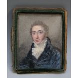 A 19TH CENTURY OVAL PORTRAIT MINIATURE OF A GENTLEMAN IN A BLUE COAT WITH WHITE CRAVAT, in leather