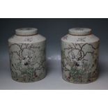A PAIR OF CHINESE CELADON LIDDED STONEWARE JARS, hand painted studies of birds perched in trees in