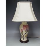 A MOORCROFT MAGNOLIA PATTERN TABLE LAMP, cream ground with typical tubelined decoration, raised on a