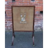 AN EDWARDIAN MAHOGANY FIRESCREEN WITH MATERIAL LINING AND STITCHED CREST WITH MOTTO 'DUM VIGOLO