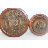 A PRESSED CIRCULAR COPPER ALLOY PLAQUE of a religious scene (Adam & Eve) and a smaller example depi