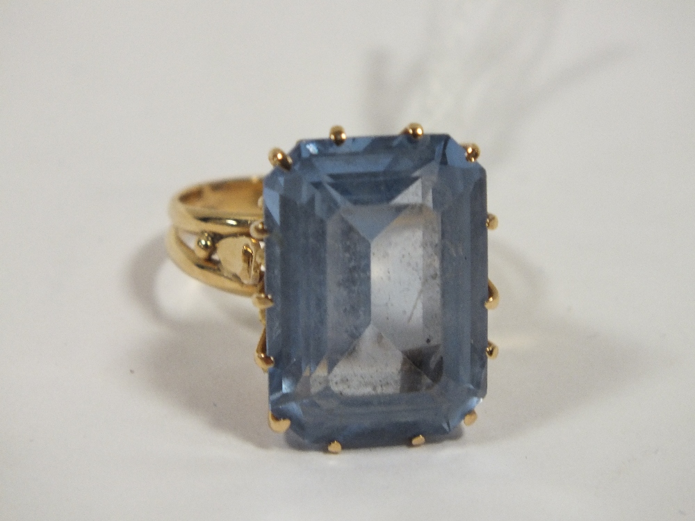 A YELLOW METAL DRESS RING SET WITH A LARGE EMERALD CUT BLUE STONE