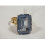A YELLOW METAL DRESS RING SET WITH A LARGE EMERALD CUT BLUE STONE