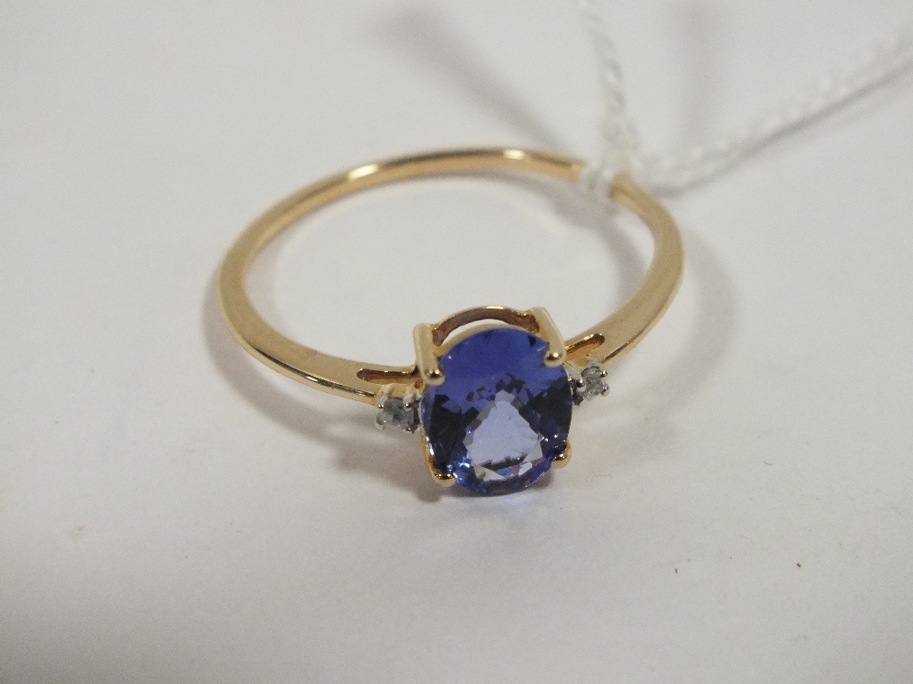 A HALLMARKED 9 CARAT GOLD TANZANITE RING, the oval tanzanite coming with a stone either side, and is