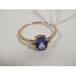 A HALLMARKED 9 CARAT GOLD TANZANITE RING, the oval tanzanite coming with a stone either side, and is