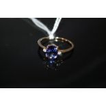 A HALLMARKED 9 CARAT GOLD TANZANITE RING, the oval tanzanite coming with a stone either side, and is