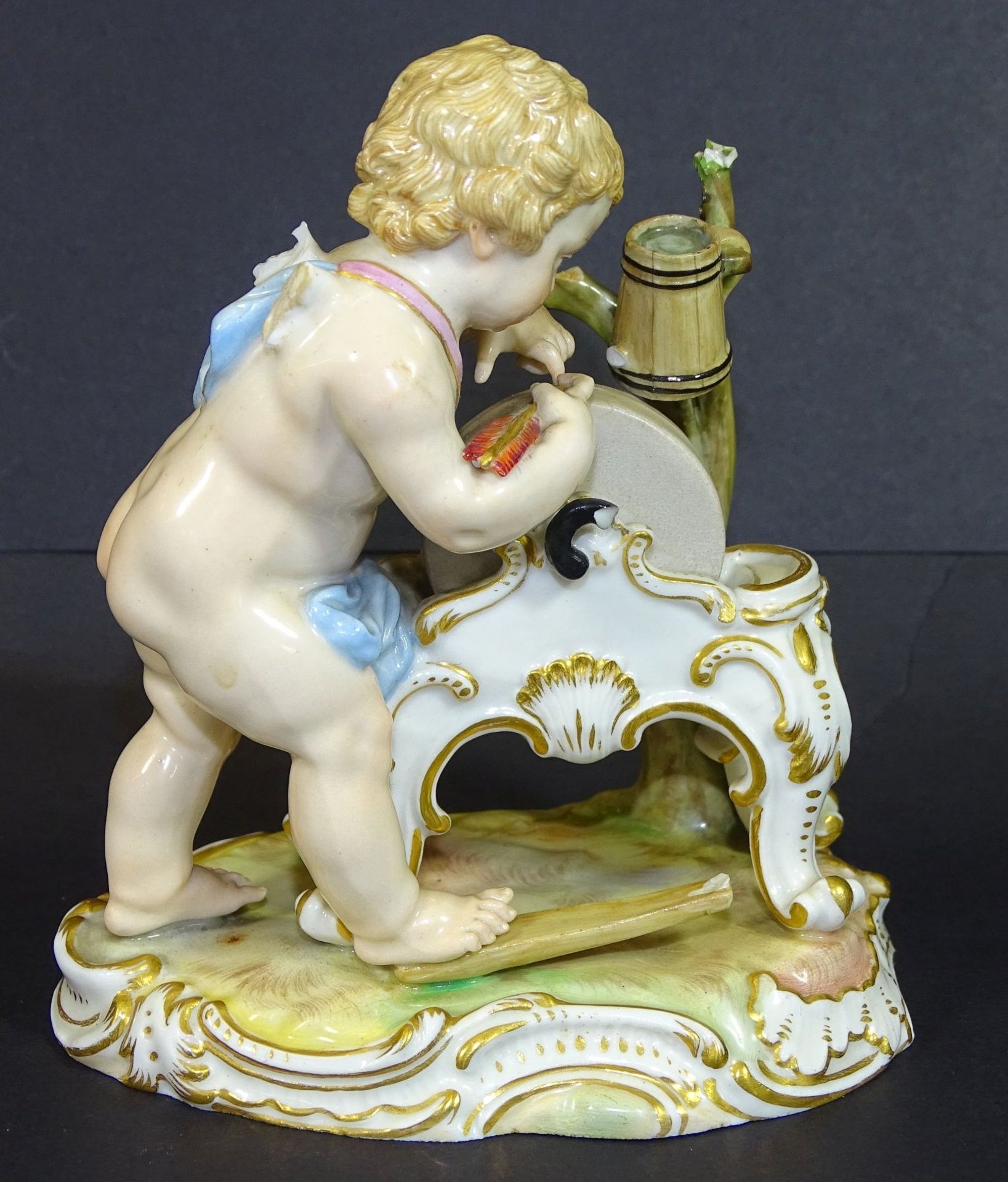 Meissen-Putto an Schleifstein,, Knauf-Schwerter, bemalt, Flügel abgebrochen, mehrmals bestossen, H-