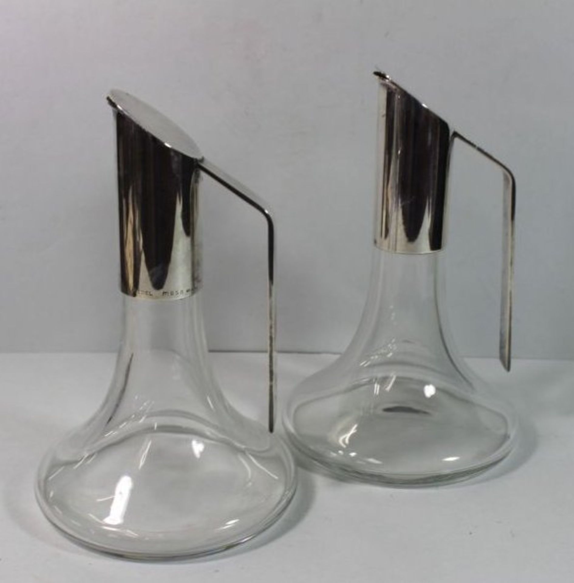 2 Schenkkannen, farbloses Glas mit Metallmontage, sign. Riedel Mesa, Italy, je ca. H-21cm.
