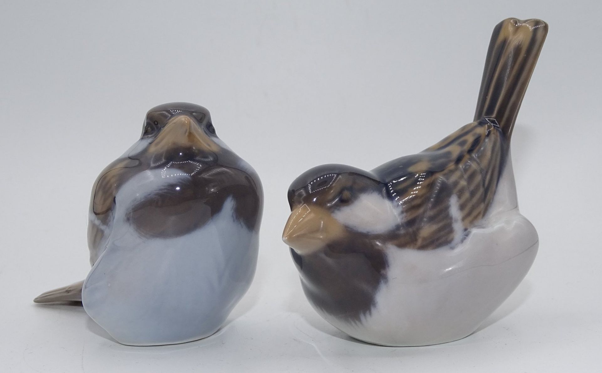2 sitzende Vögel "Royal Copenhagen", bemalt, H-max. 8 c