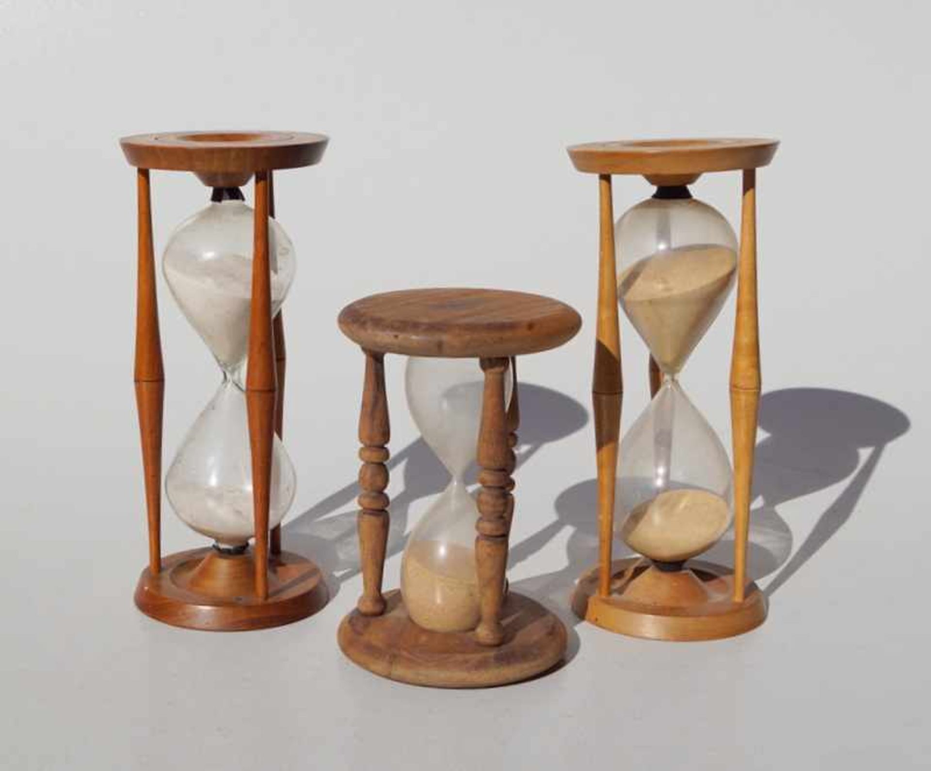Sammlung von drei Sanduhren/ Stundengläsern Gestell aus Holz mit Glaskolben, Sandfarbe braun und