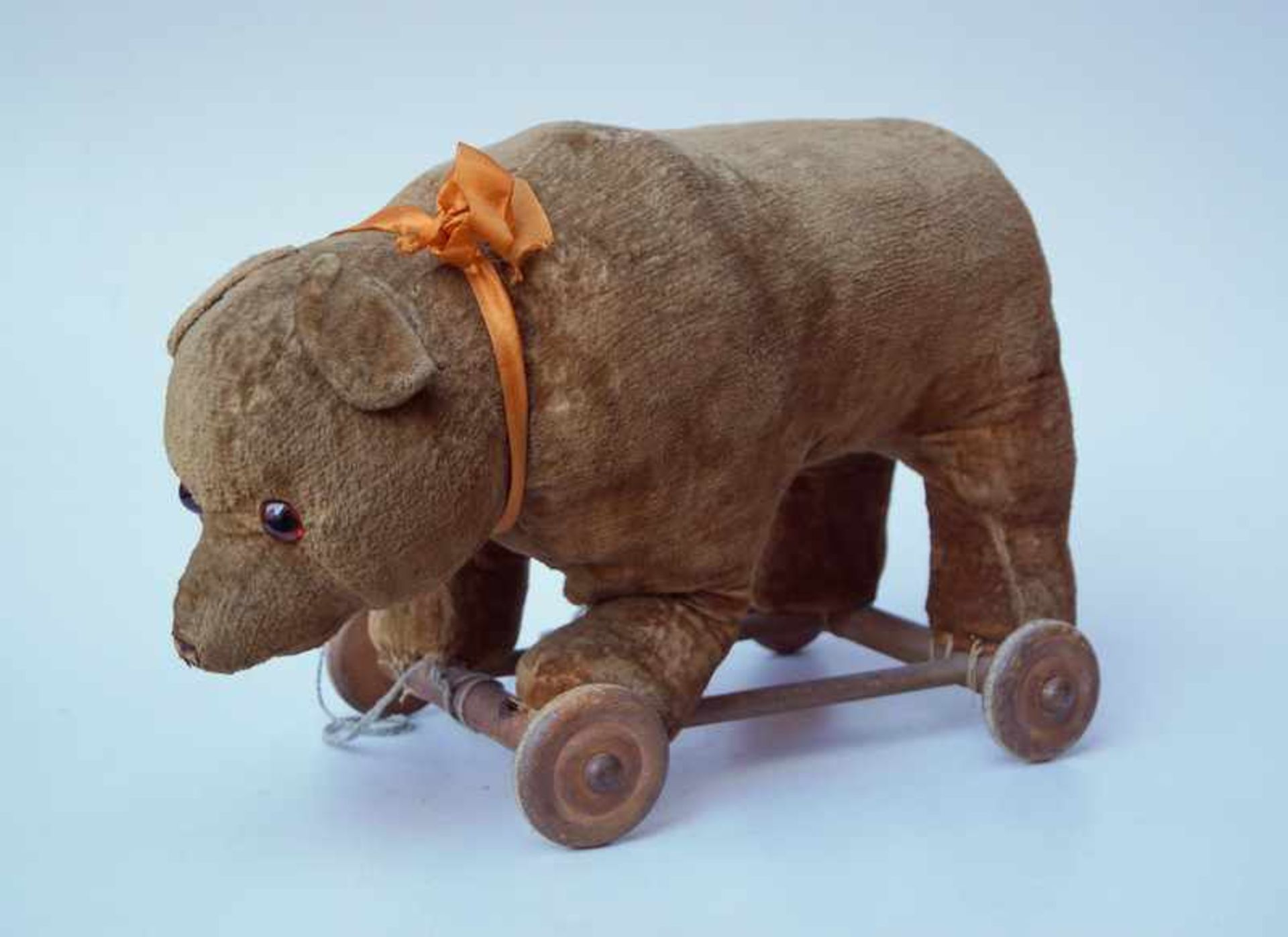 Rollbär, um 1960Rollgestell aus Holz, mit hölzernen Rädern, Bär mit braunem Stoff und