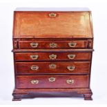 A George III oak bureau in two sections the fall front enclosing a compartmentalised interior with