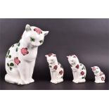 Four graduating Plichta cat figures all hand painted with flowering clovers and highlighted tails,