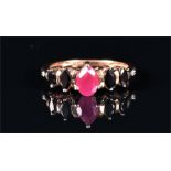 A 9ct yellow gold, ruby and sapphire ring set with a pear-cut ruby flanked with four marquise cut