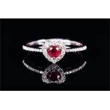 A delicate 18ct white gold, diamond, and ruby ring set with a heart-shaped ruby surrounded by a halo