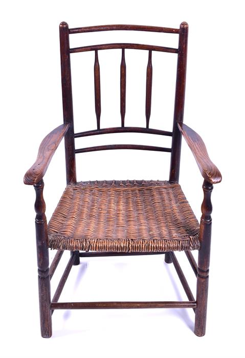 A 19th century oak country stick back armchair with wicker seat and supported on turned legs with