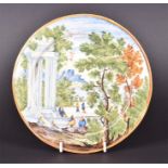A mid 18th century Italian Castelli Maiolica plate figures sit and stroll beside temple ruins,