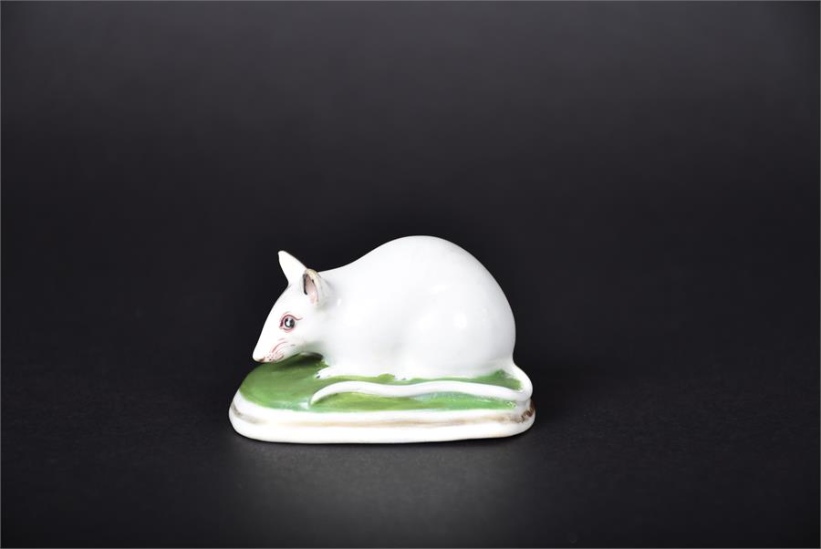 An early 19th century English porcelain model of a mouse, possibly Derby seated on a green cushion