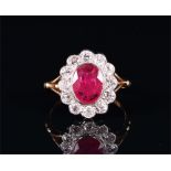 An 18ct yellow gold, diamond, and ruby cluster ring set with an oval cut ruby of approximately 1.