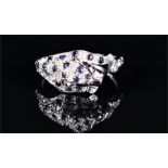 A 9ct white gold, diamond, and sapphire leopard ring in the style of Cartier, the stretching leopard