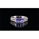 A 14ct white gold, diamond, and tanzanite ring set with three graduated oval-cut tanzanites, the