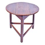 An 18th century or later oak cricket table the circular top on chamfered legs joined by