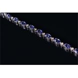 An 18ct white gold, diamond, and tanzanite bracelet comprising of eighteen oval-cut tanzanites of