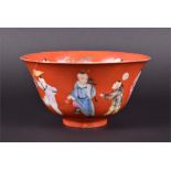 A 19th century Chinese porcelain bowl depicting numerous figures in polychrome enamels on a red