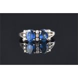 A white metal, diamond, and sapphire ring set with two oval-cut blue sapphires of approximately 1.90