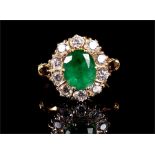 An 18ct yellow gold, diamond, and emerald cluster ring set with an oval-cut emerald of approximately