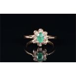 A 9ct yellow gold, diamond, and emerald cluster ring set with an oval-cut emerald of approximately