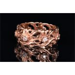 A 14ct rose gold and diamond eternity ring the stylised openwork and with floral decoration set with